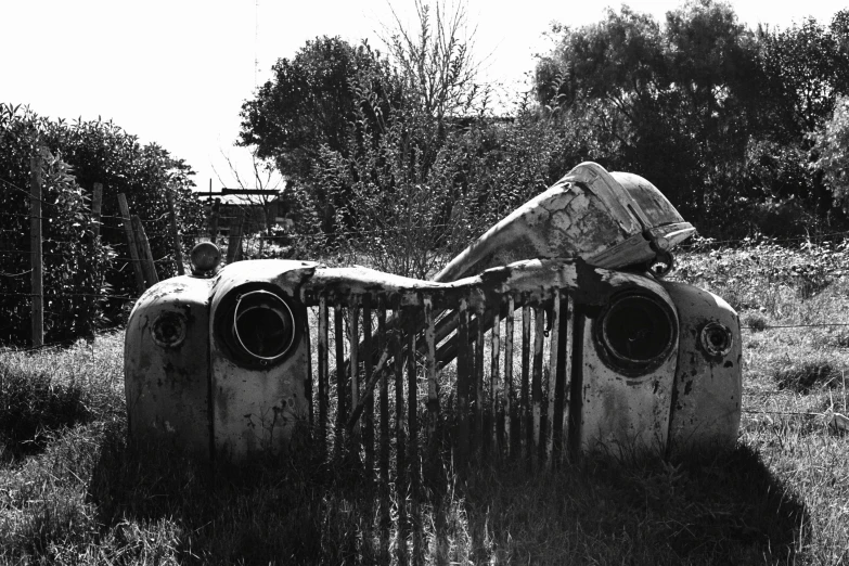 an old car in the middle of a field covered in weeds