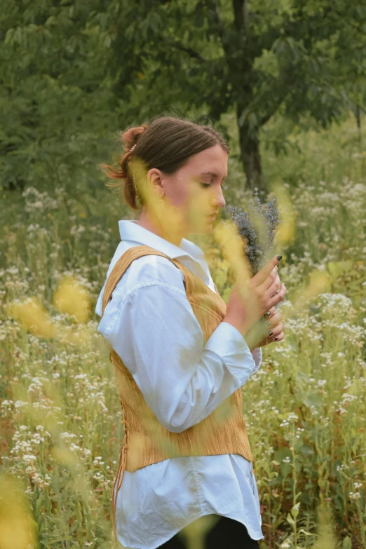 a woman in an old dress stands amongst tall weeds