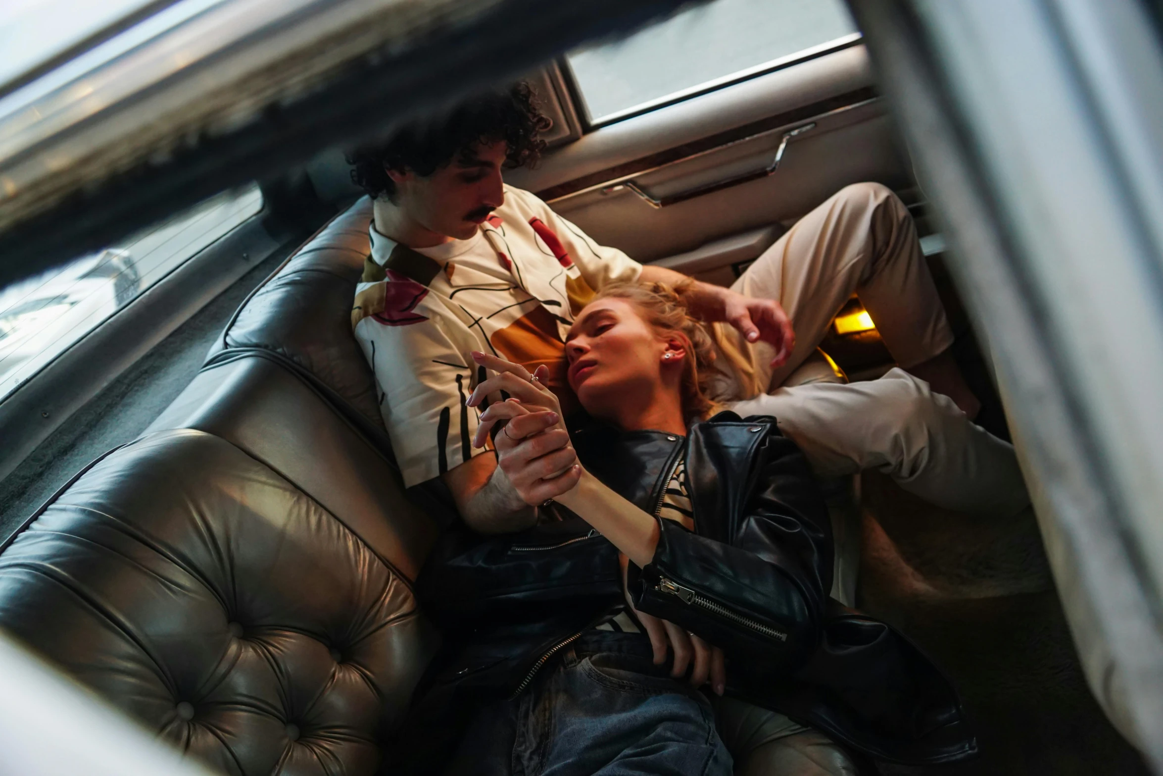 a man and woman sitting next to each other in the back seat of a car