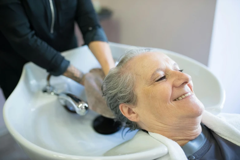 an elderly woman gets her hair brushed in the salon