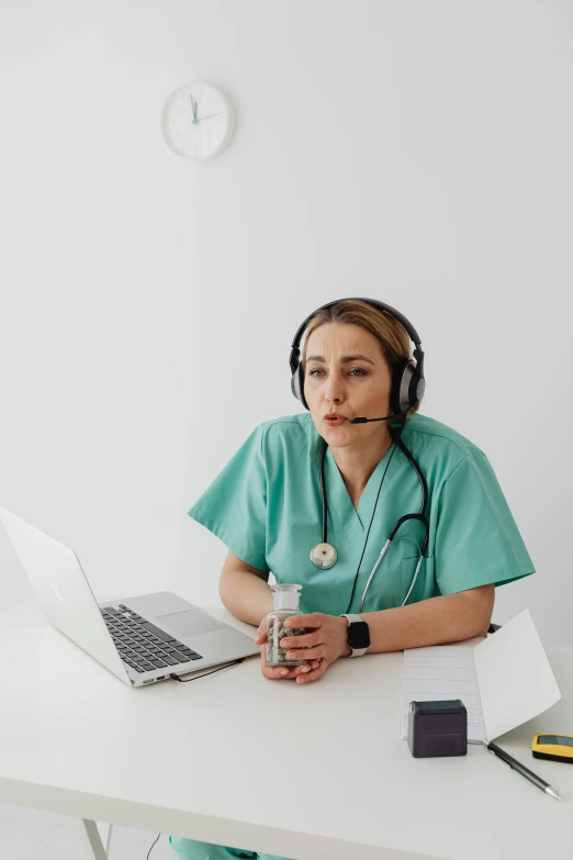 a nurse sitting at a white desk with her laptop