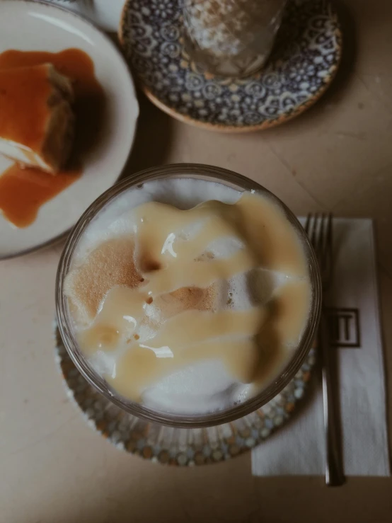 the glass is filled with liquid next to a plate with a pastry on it