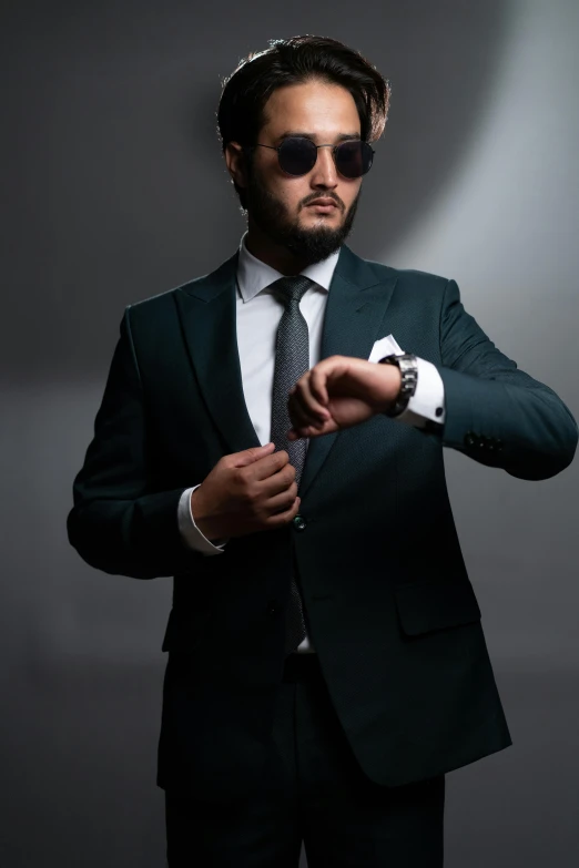 a man with glasses holding a gun, wearing a dark colored suit