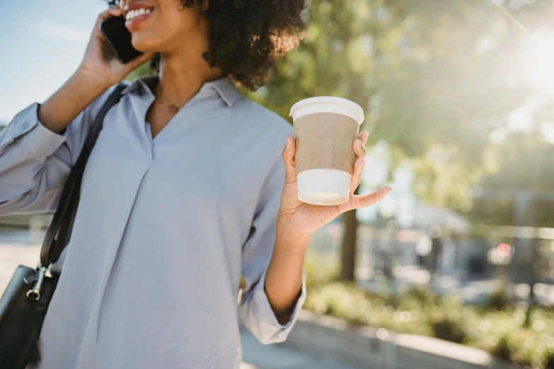 the woman is talking on her cell phone while holding her coffee