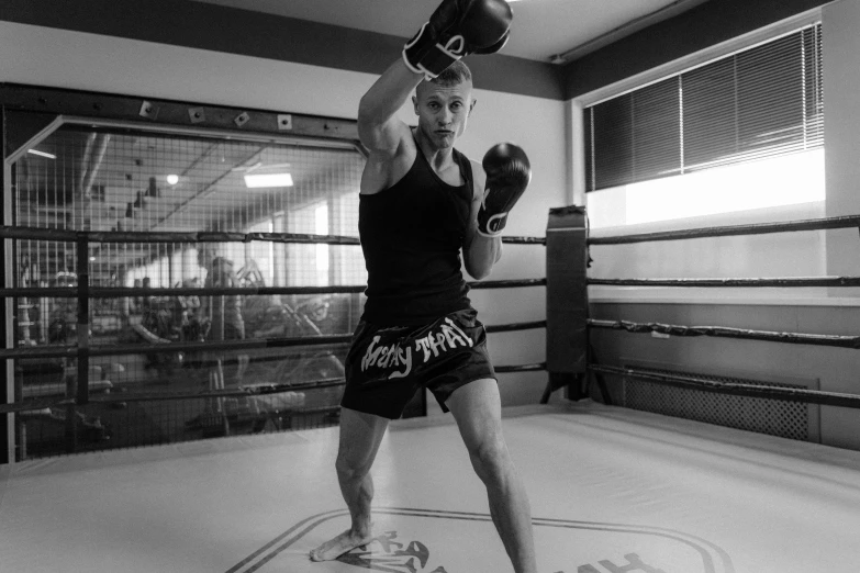 man standing in the middle of a boxing ring wearing shorts and a cap