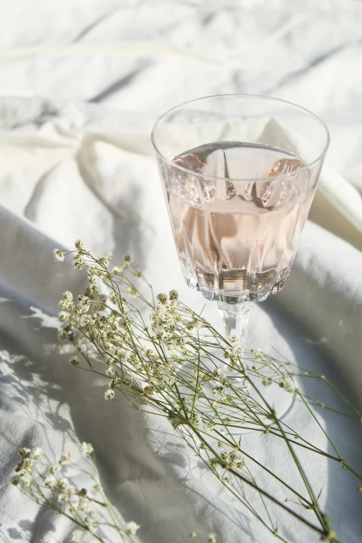 the glass is full of liquid with flowers in the background