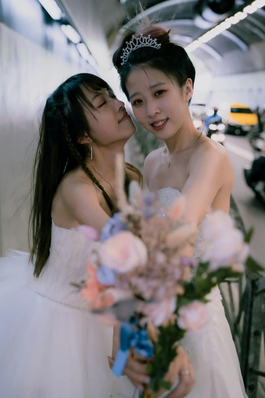 two young ladies in dresses holding flowers in front of the camera