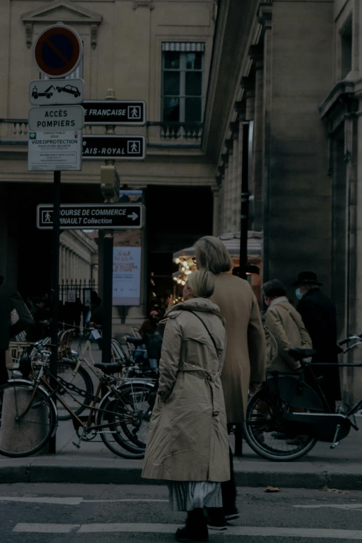 a woman in a trench coat walking by the corner