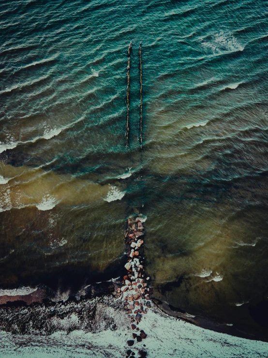 two people standing on a pier near the ocean