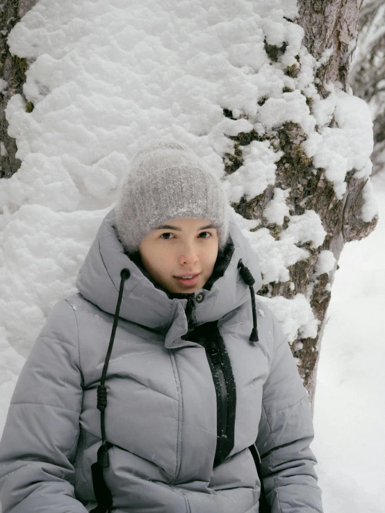 a person in gray jacket sitting in front of a tree