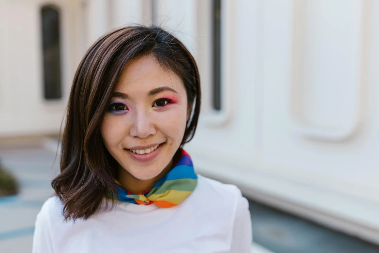 the woman with dark hair and a rainbow colored scarf on smiles broadly