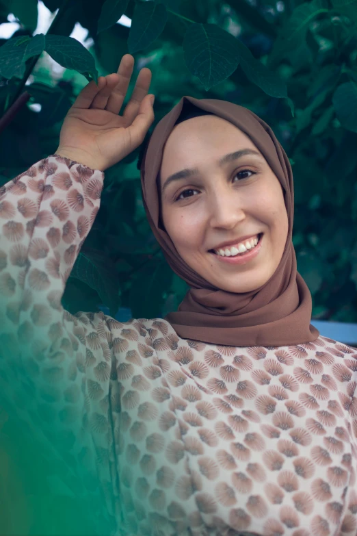 woman in a brown hijab smiling with green background