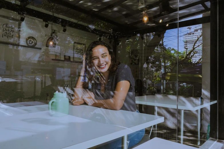 a woman sitting at a table smiling with a cell phone