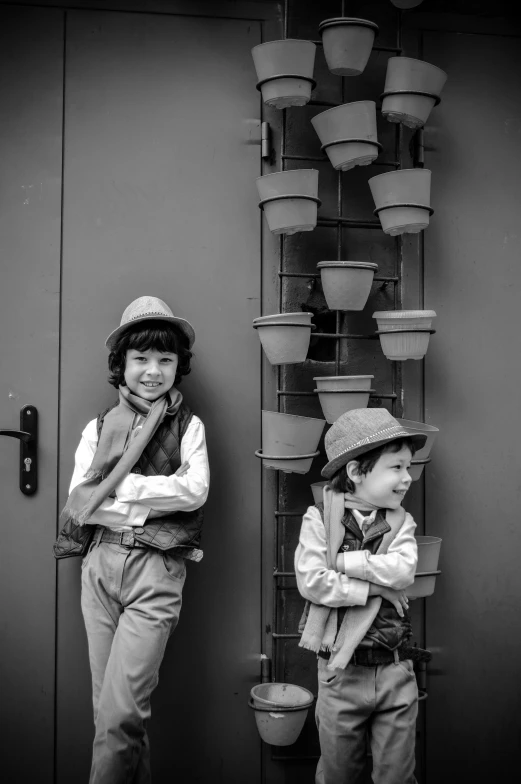 two boys standing in front of a tall metal planter
