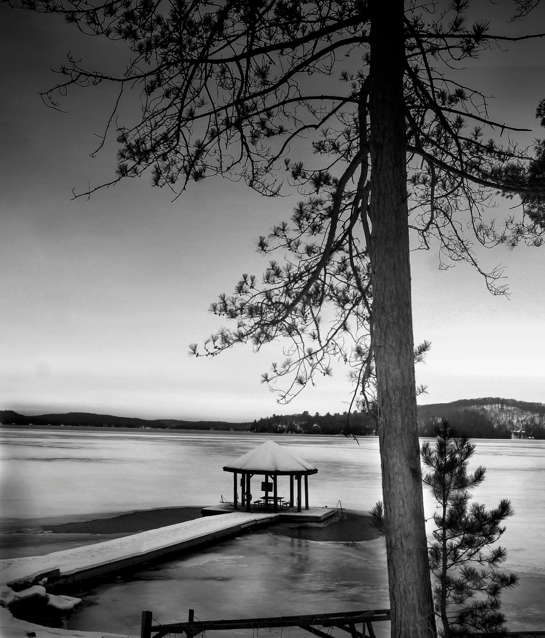 an empty bench near the water in a black and white po