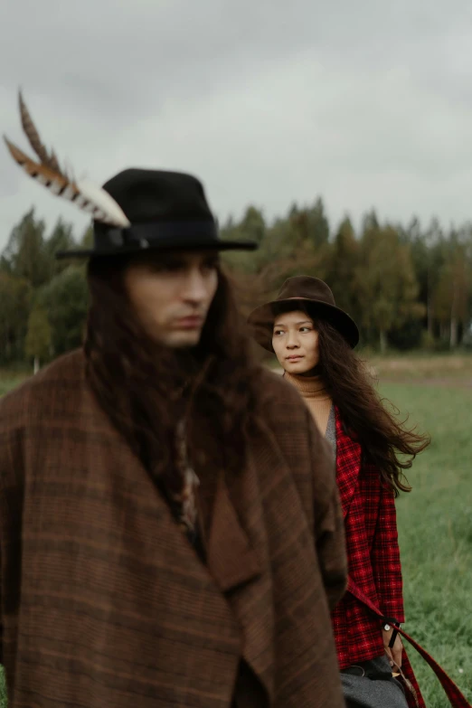 a woman and man wearing hats are in a field