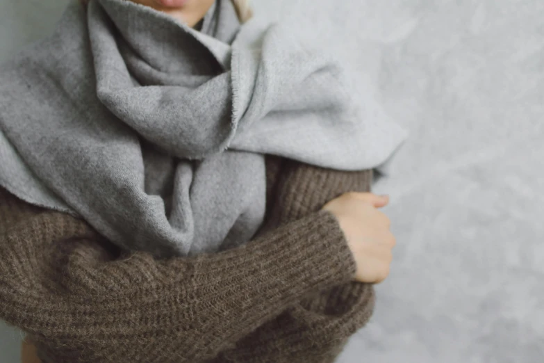 a woman in a brown sweater and grey scarf