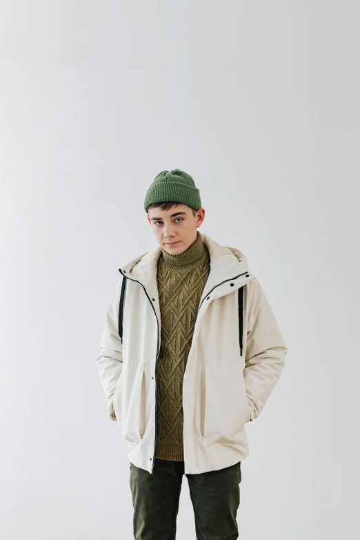 a boy with a hat on posing in a white coat