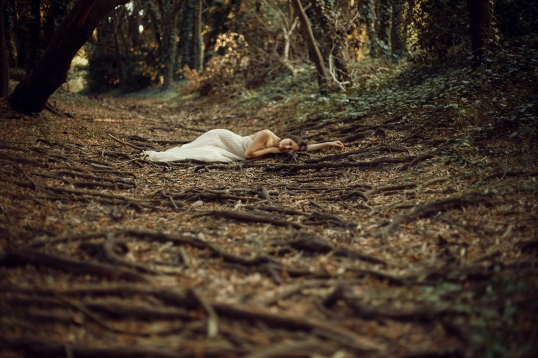 the woman is laying down in the woods