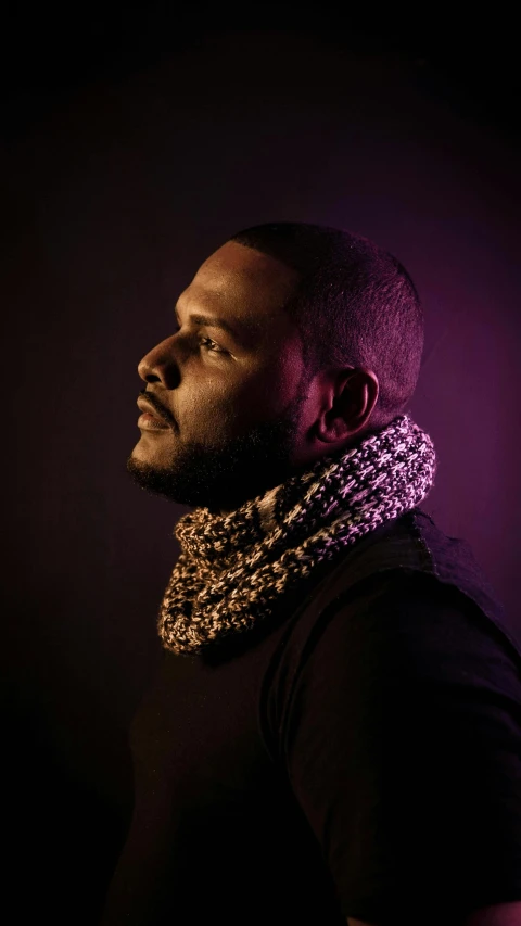 a man in a dark shirt wearing a cowl scarf