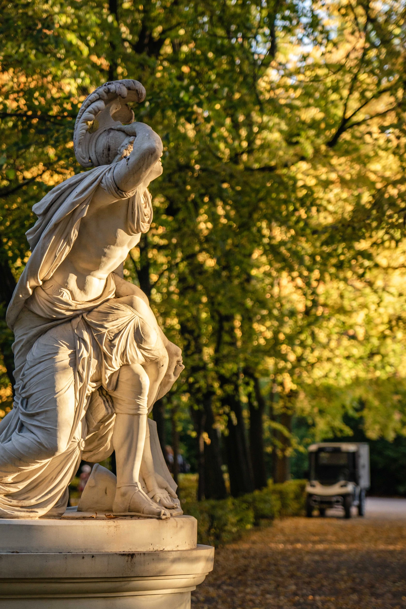 a white statue is outside in front of some trees