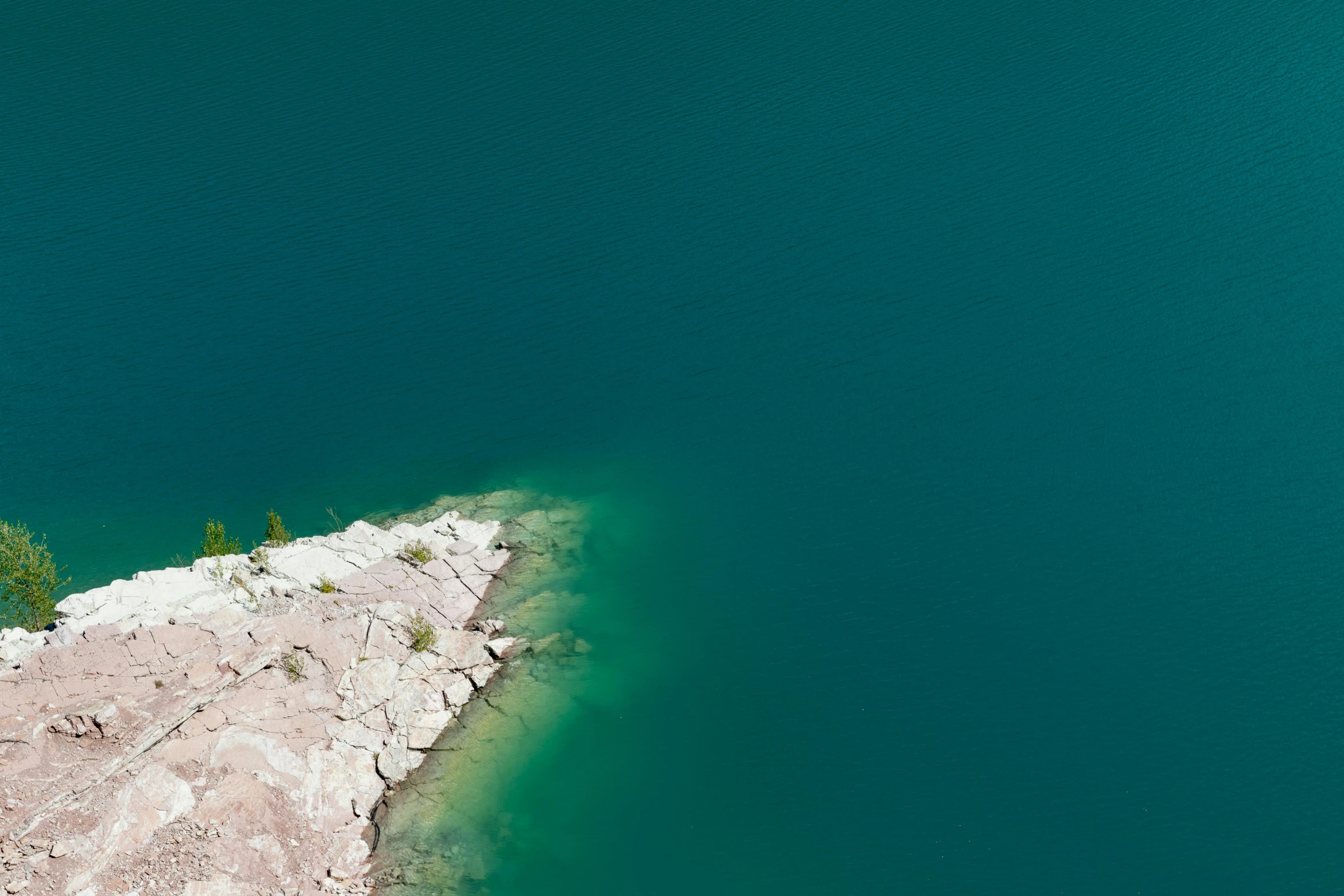 a person stands at the end of a ledge near some water