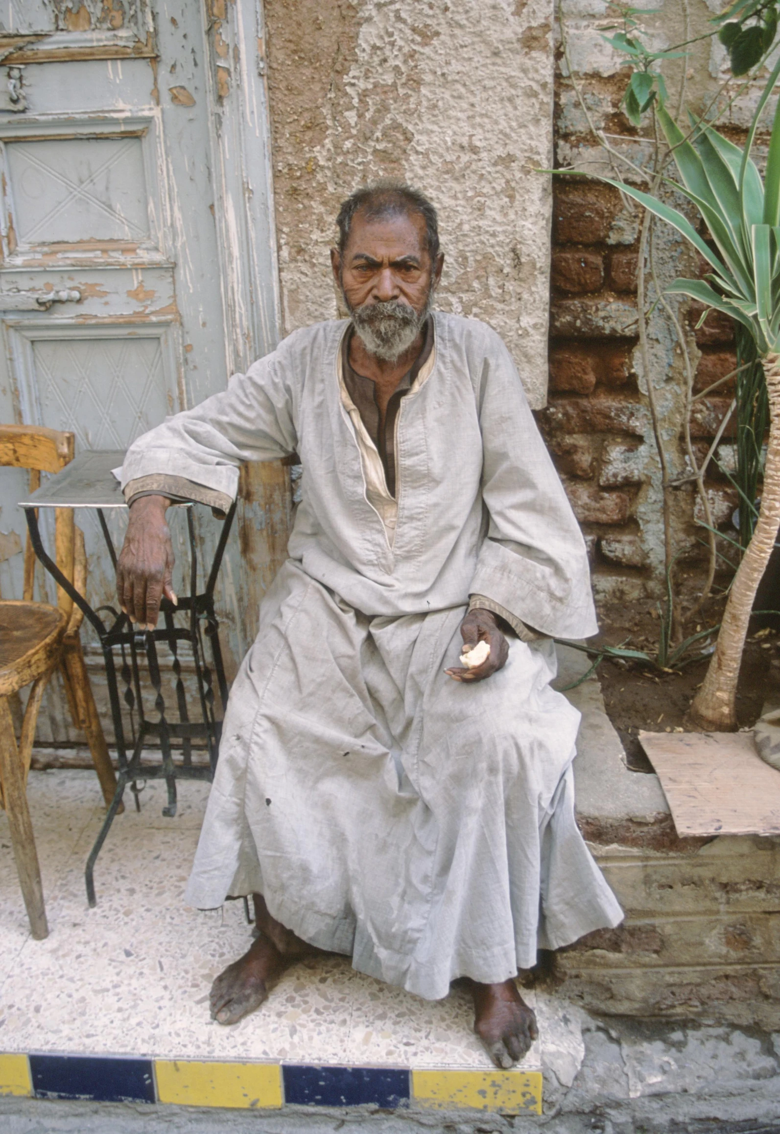 a old man with gray clothes sitting on the stairs