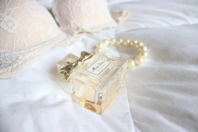 a pearl celet and perfume bottle on a bed