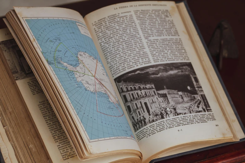 the opened book contains images of ships and towns