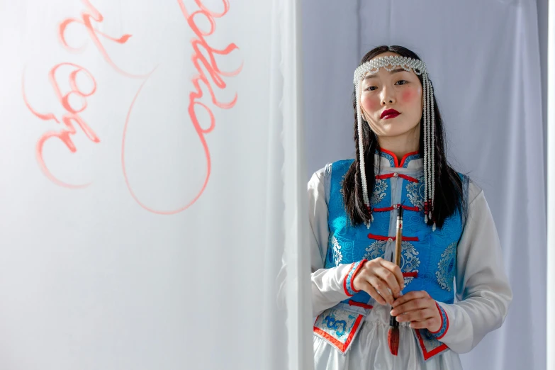 an asian child wearing a blue and white dress standing with a wand