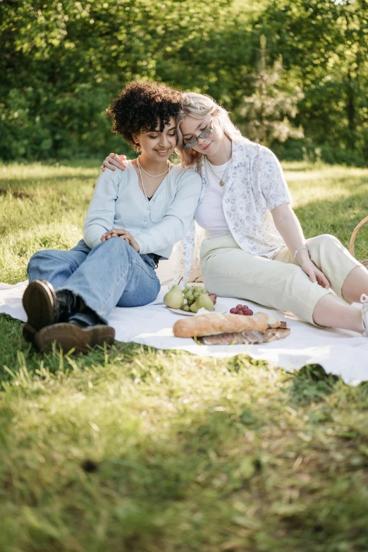 a couple of women sitting on a blanket in the grass