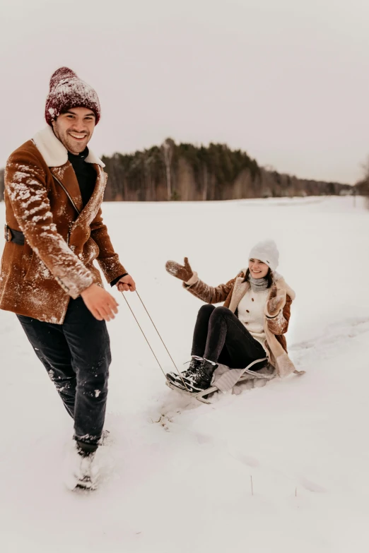 a couple playing with a snow sled in the snow