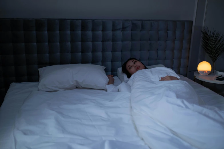 a woman lays in bed at night with a light on