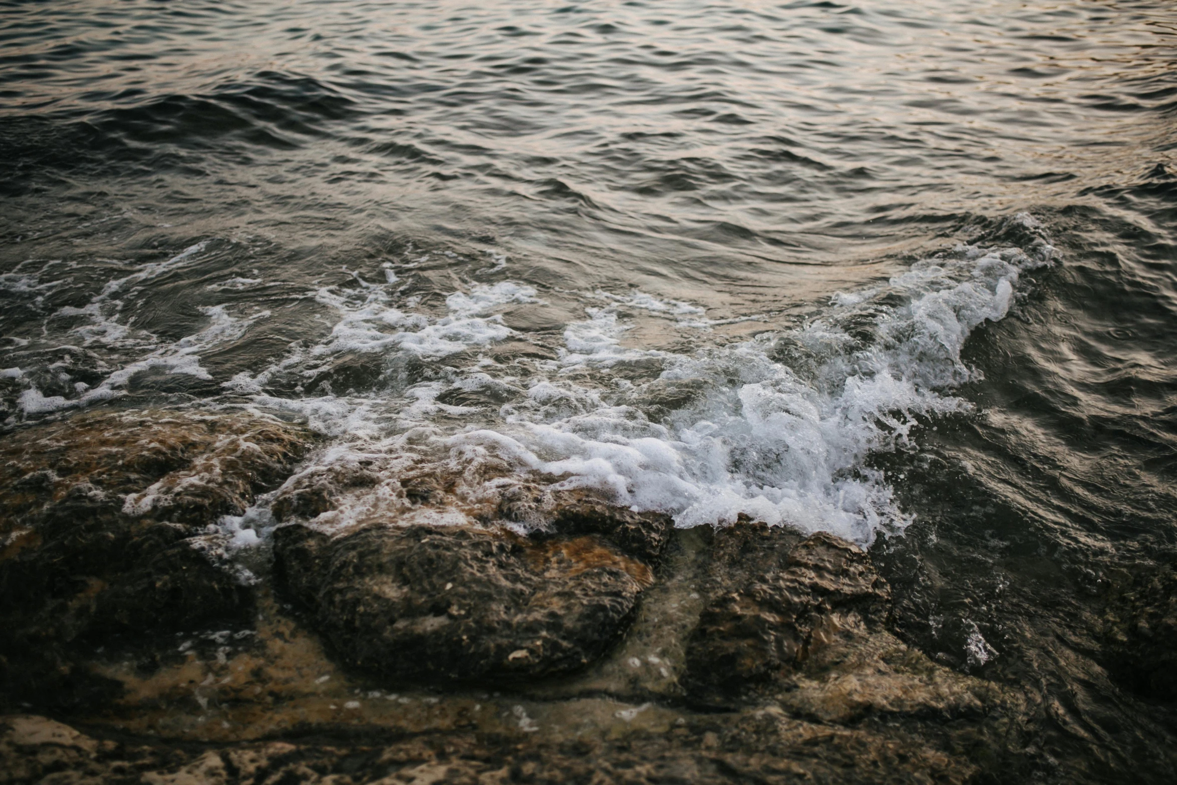 waves crash against rocks and the ocean at sunset