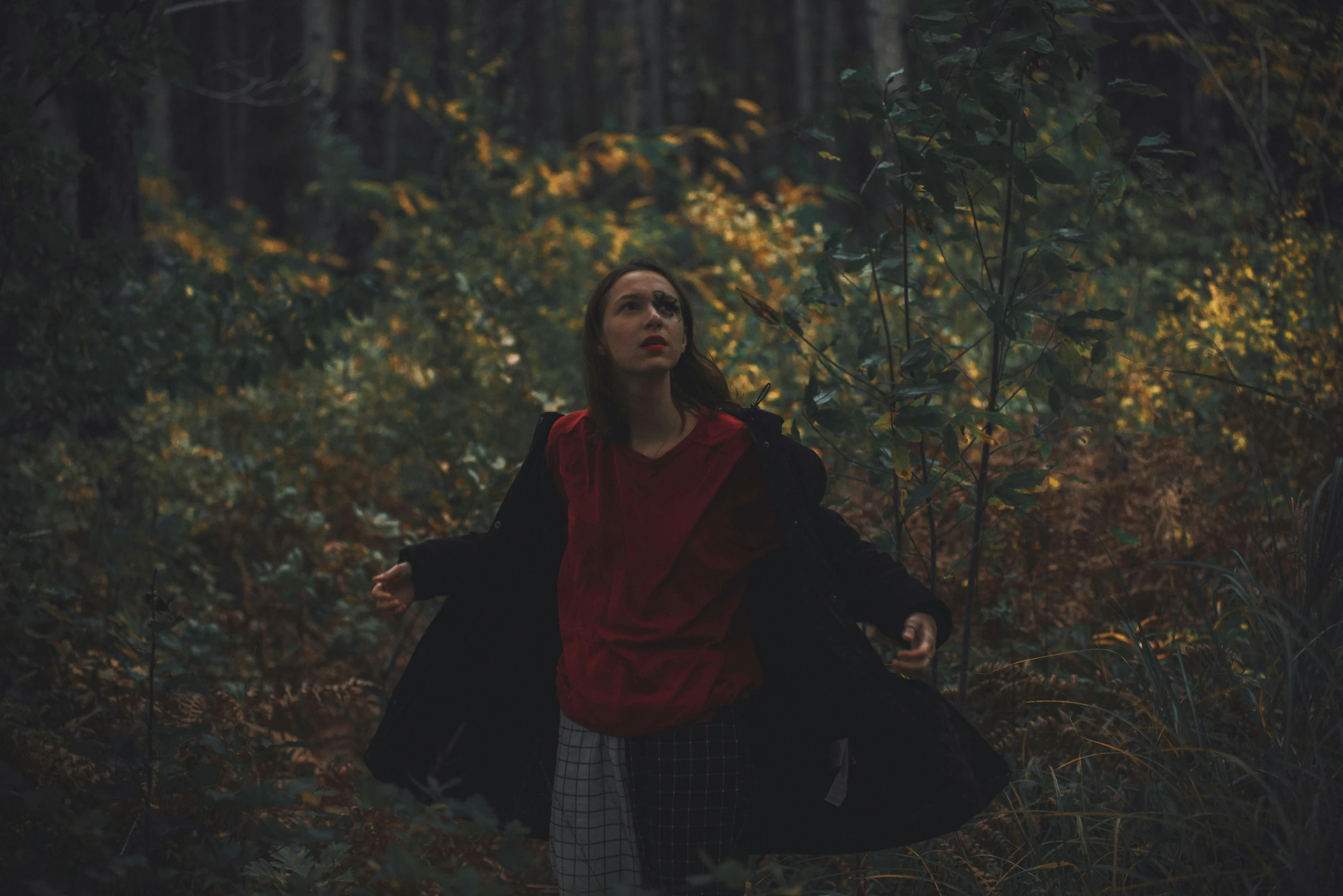 a woman in the woods is holding an umbrella