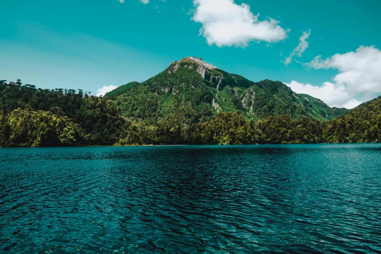 a body of water sitting below a mountain on a hill