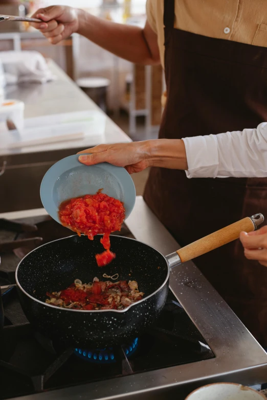 woman stirring tomato sauce over stove top with cooking utensils