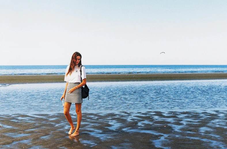 a woman holding a purse and standing in the water