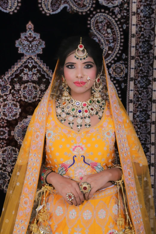 indian model in yellow bridal outfit in front of an intricate rug