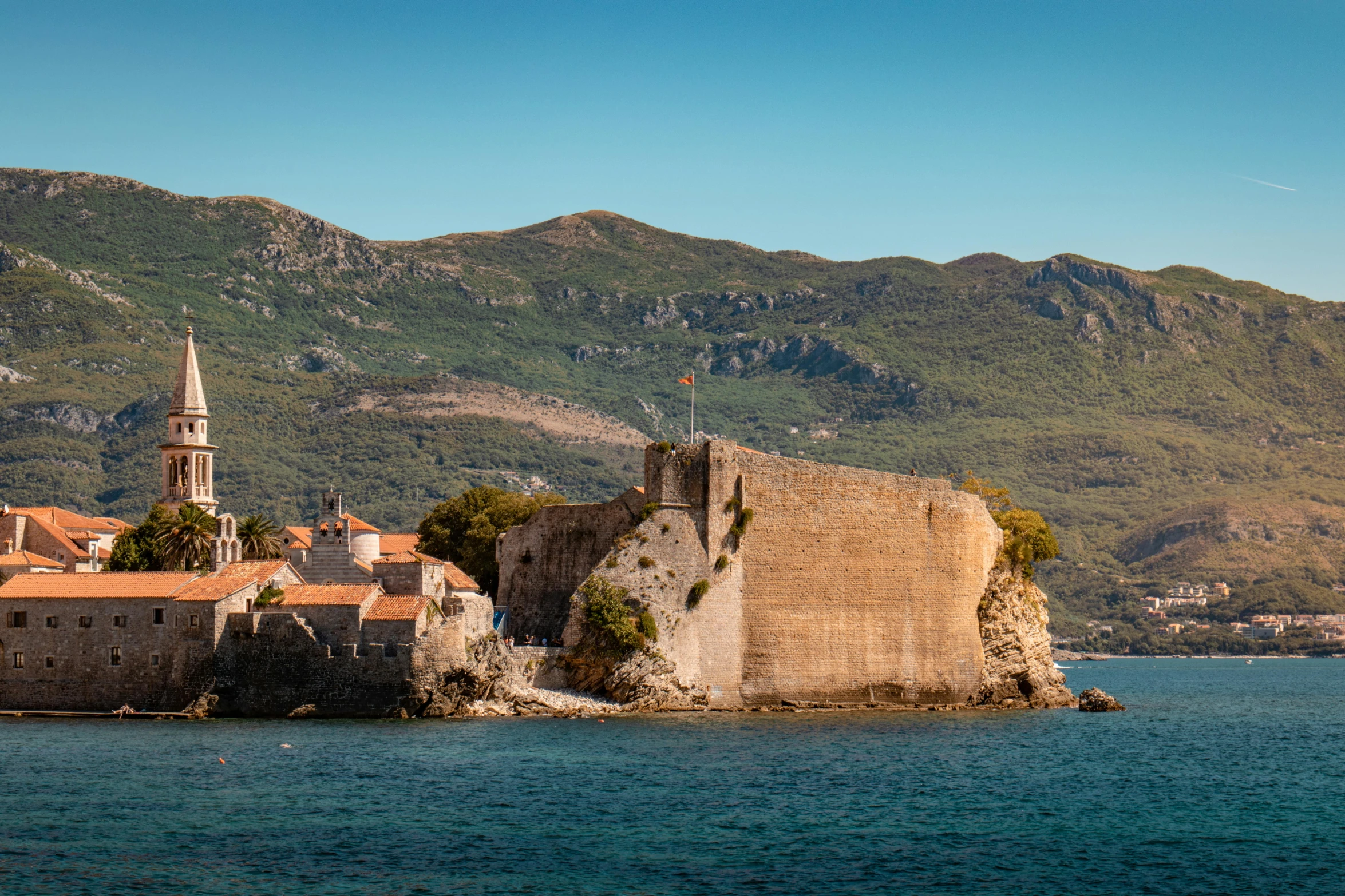 the buildings are next to a large stone wall