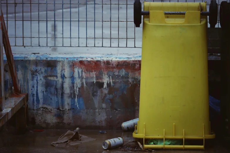 a yellow plastic box is standing next to a fence