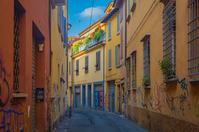 a narrow alley way with several old buildings and graffiti all over the walls