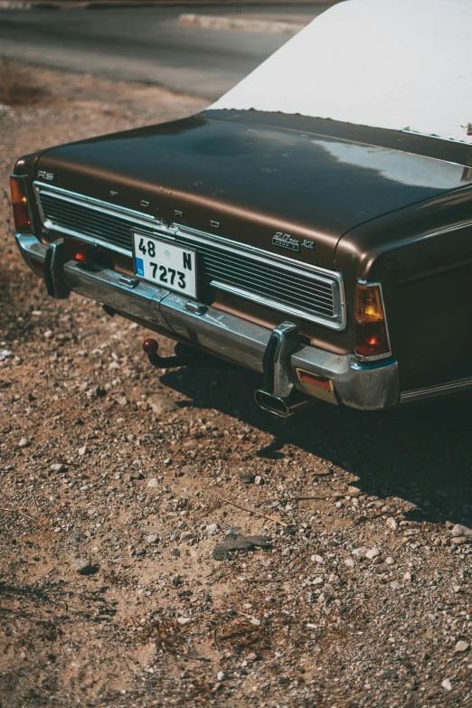 a black car parked on the side of a dirt road