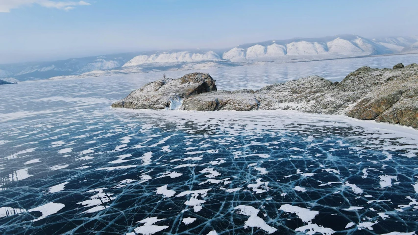 snow and ice melting on the shore of water