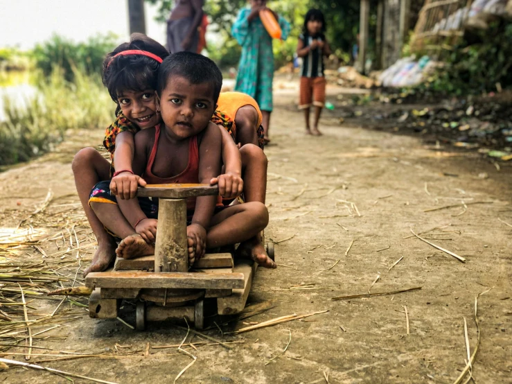 two young children are sitting on a cart