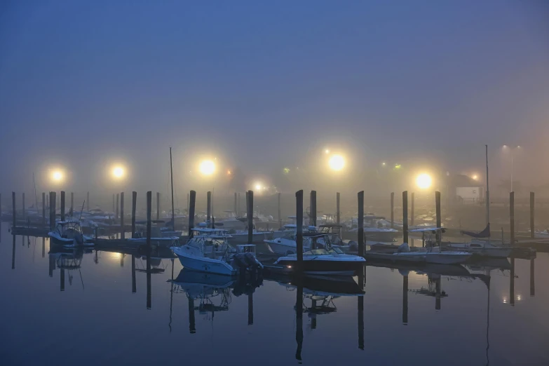 boats are docked in a calm bay on a foggy night