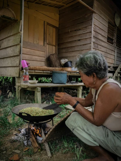 woman cooking on a pan over an outdoor fire