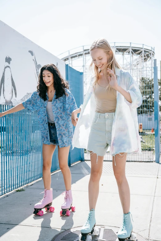 three young women are on skateboards in front of a roller coaster