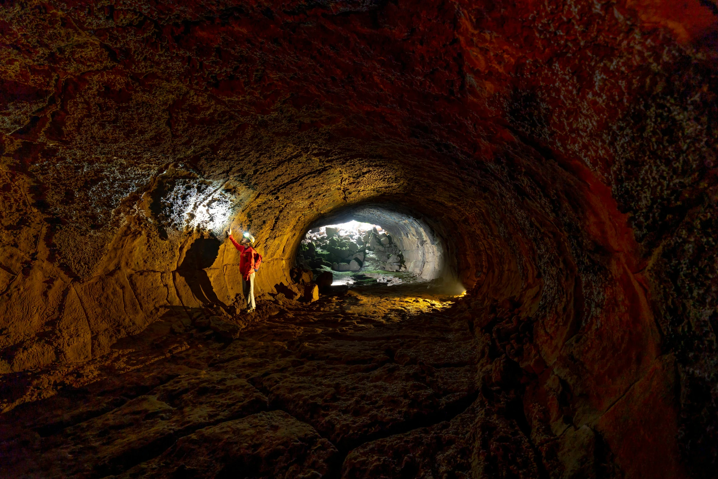 a person standing inside a rocky tunnel with dark shadows