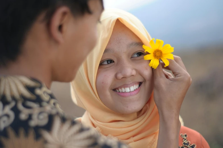 a woman standing next to another woman and holding a flower